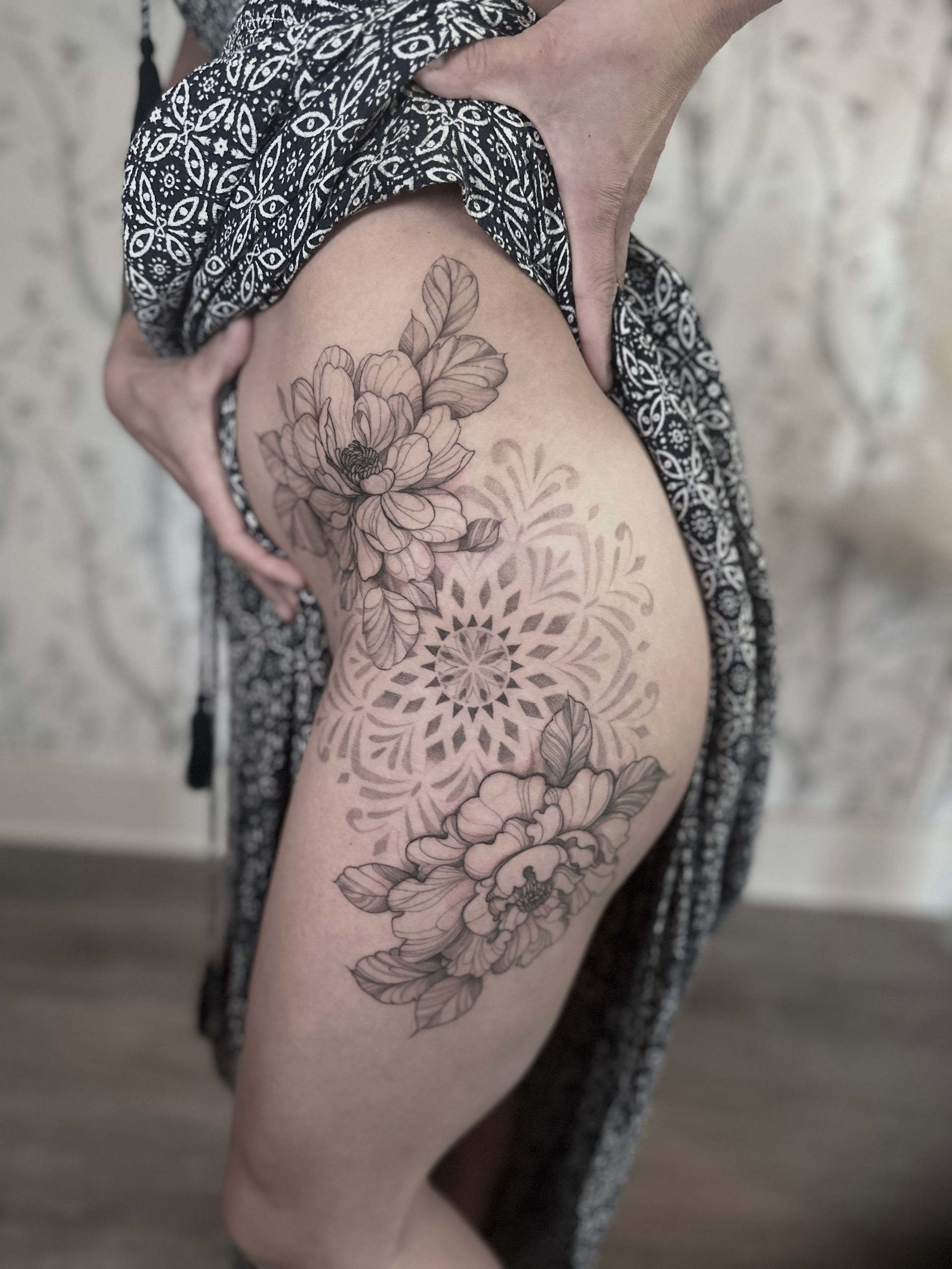 A woman has a tattoo of peony floral with a mandala
