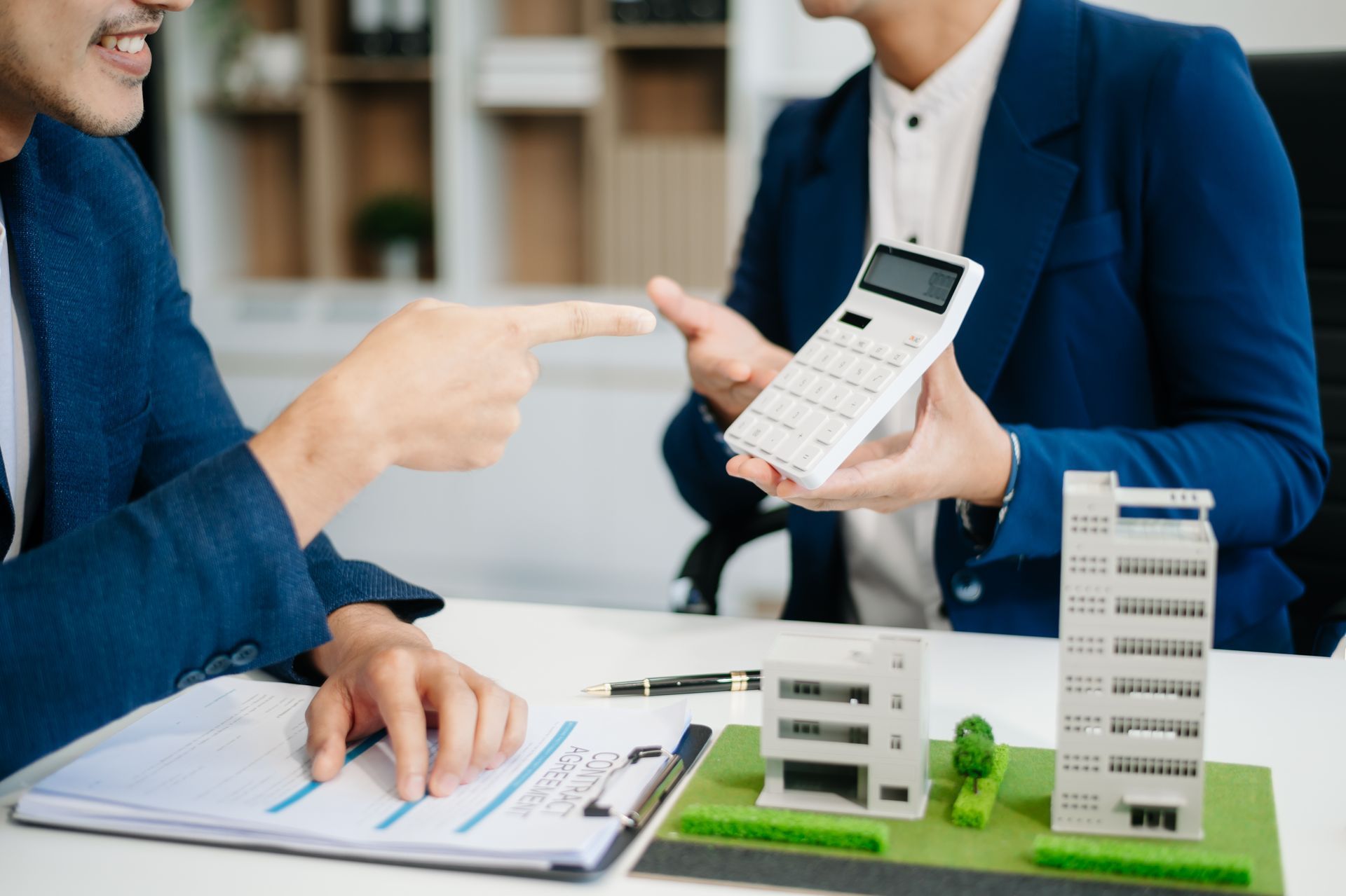 A man is giving a calculator to another man while sitting at a table.