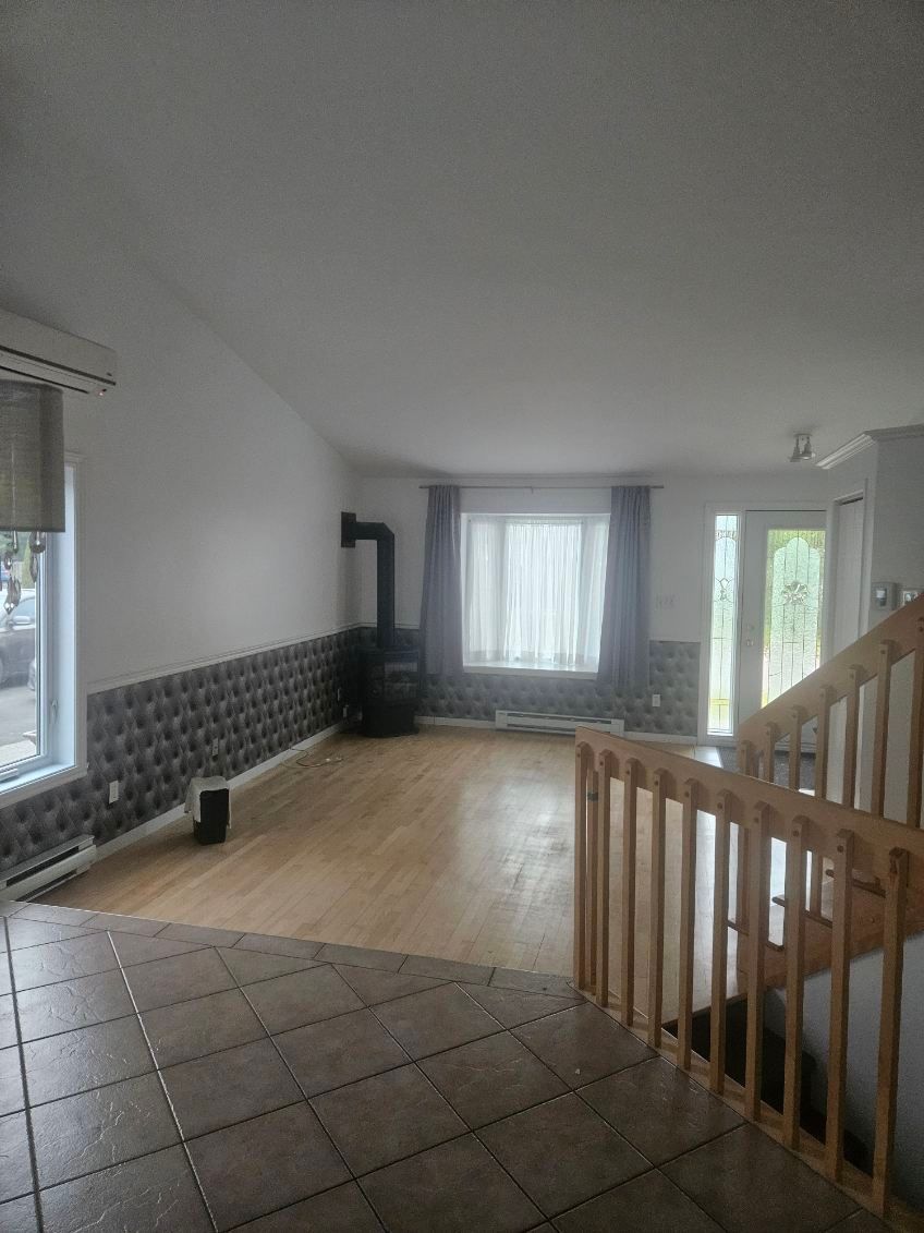 Intérieur du salon avec parquet, cheminée et escalier.