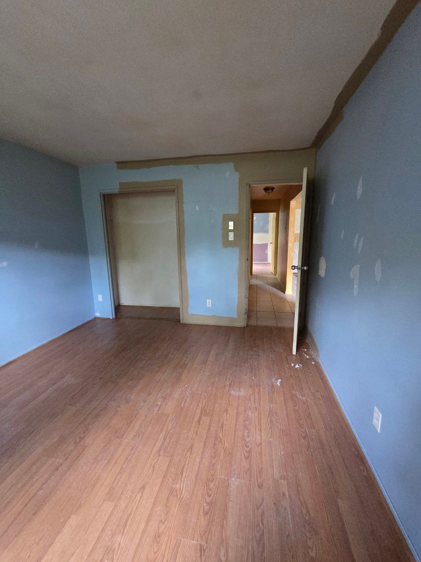 Pièce vide aux murs bleu clair, au sol imitation bois et avec une porte.