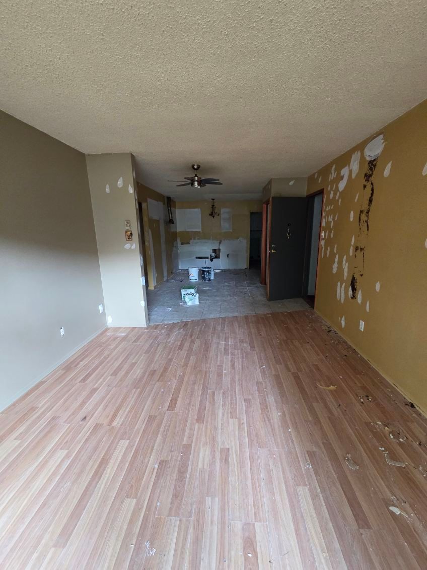 Pièce en cours de rénovation avec murs apparents, parquet et matériel de peinture.