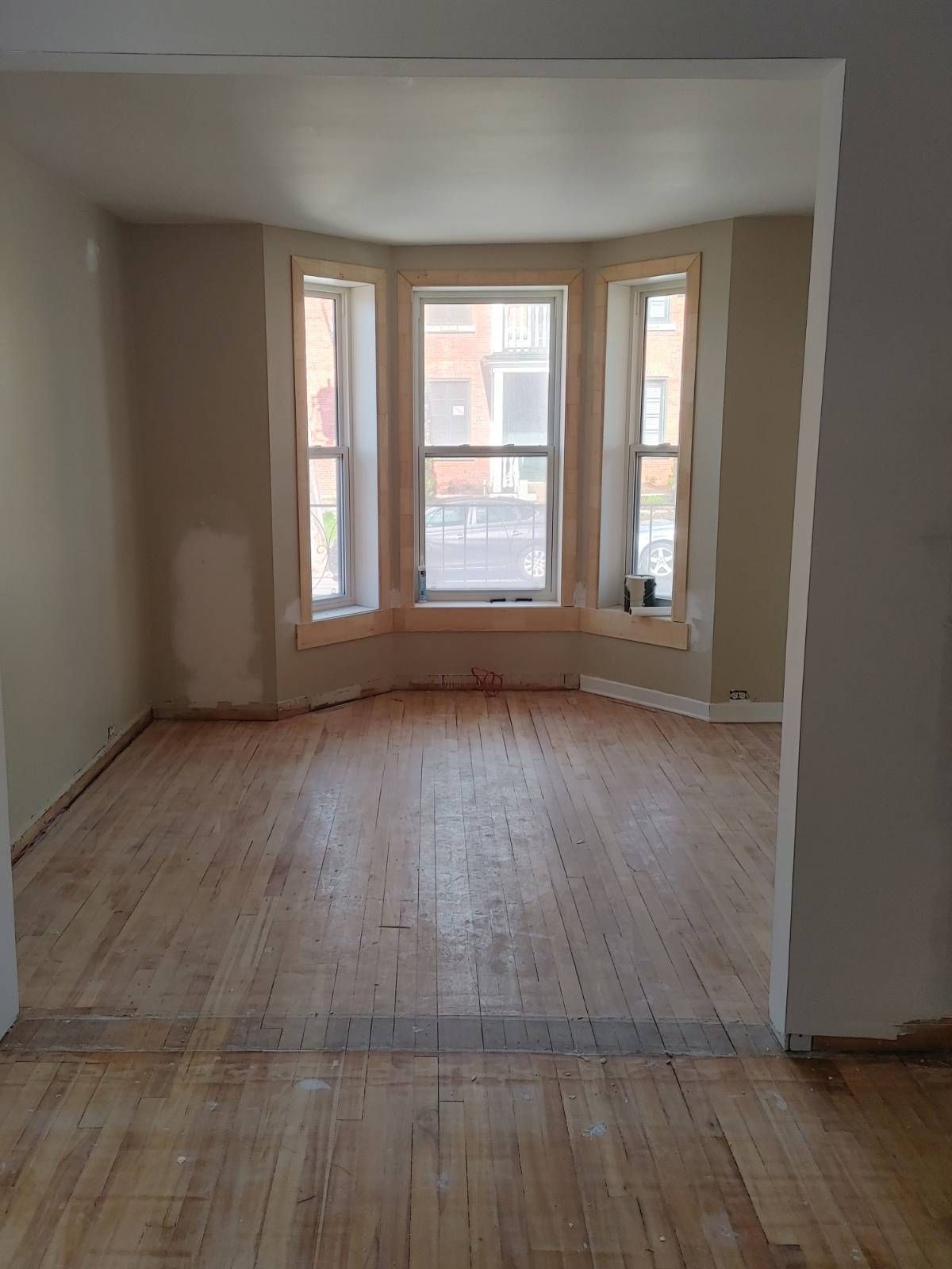 Pièce vide avec bow-window et parquet.