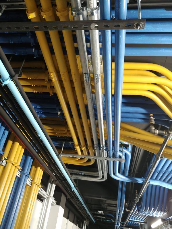 Vue aérienne d'un plafond avec des tuyaux colorés : jaunes, bleus et gris.