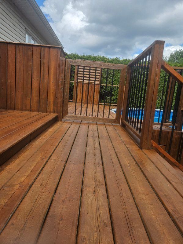 Terrasse en bois avec un portail donnant sur une piscine. Bois brun, balustrade en métal noir et ciel bleu.