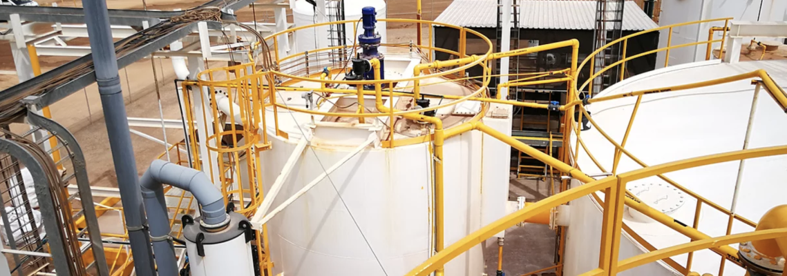 a large white tank with a yellow railing in a factory .