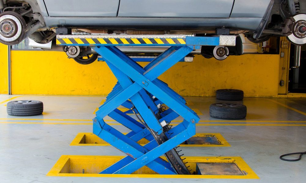 A Car Is Sitting on A Scissor Lift in A Garage — Al's Mechanical & 4WD Grafton Repairs in Grafton, NSW
