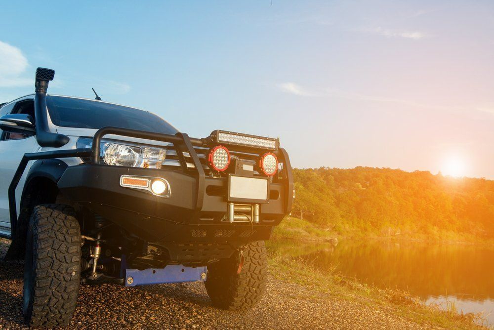 A Jeep Is Parked on A Dirt Road Next to A Body of Water — Al's Mechanical & 4WD Grafton Repairs in Grafton, NSW