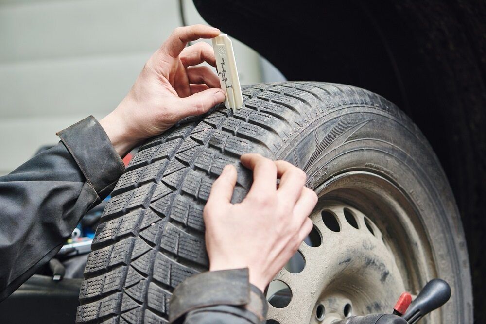 Tyre mechanic measuring wear on a tyre
