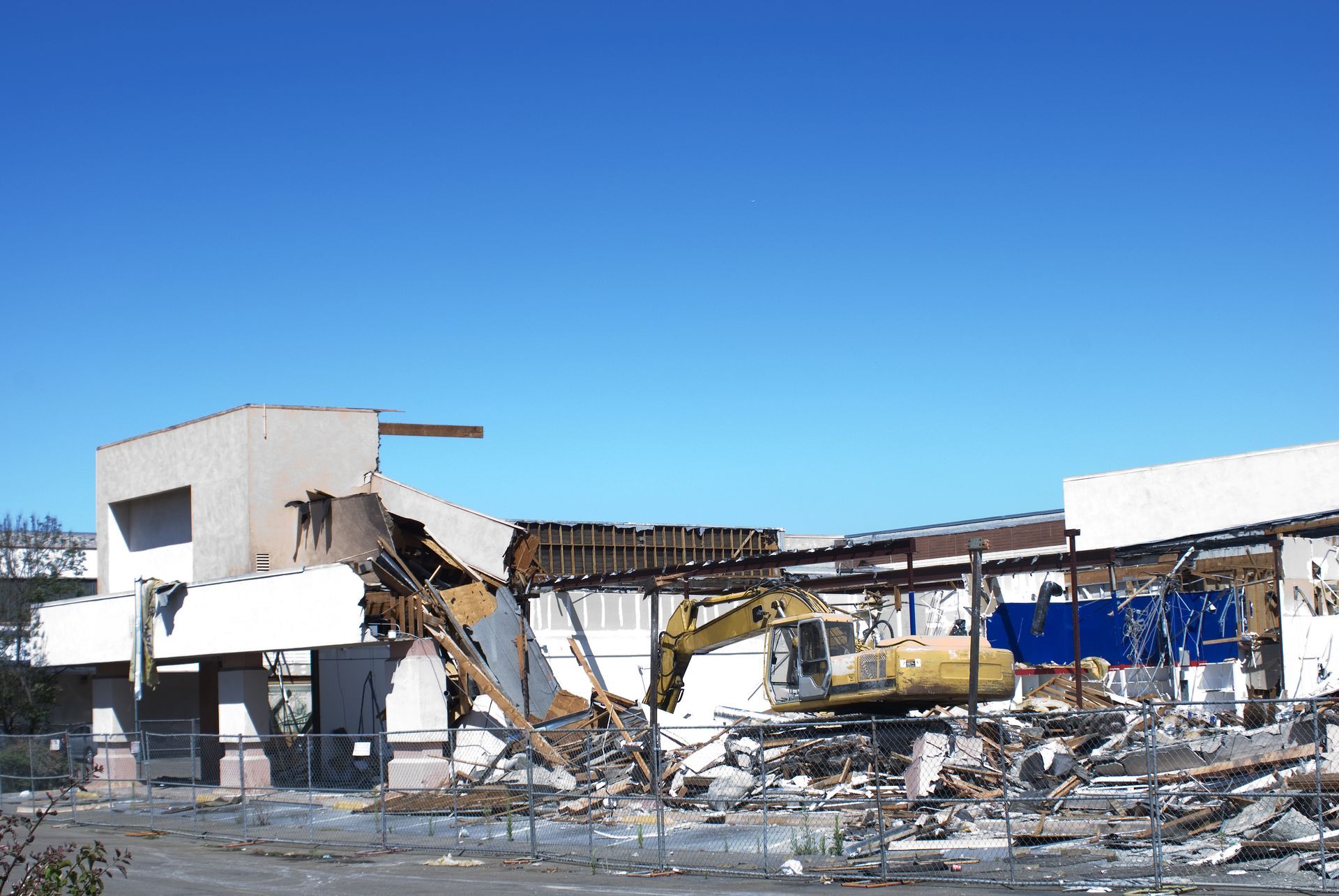 A large yellow excavator is demolishing a building.