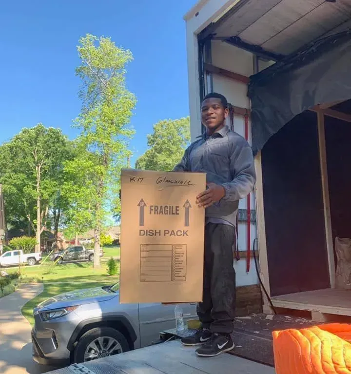 A man is holding a cardboard box that says fragile dish pack