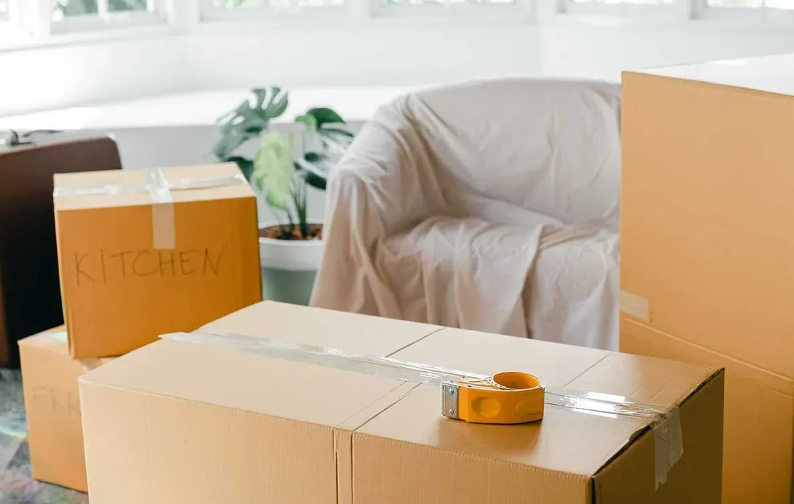 A living room filled with cardboard boxes and a chair.