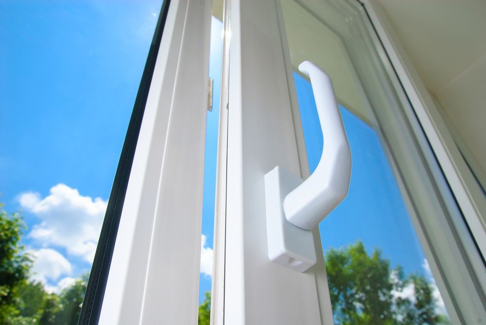 Un primer plano de una ventana de plástico blanca con una manija.