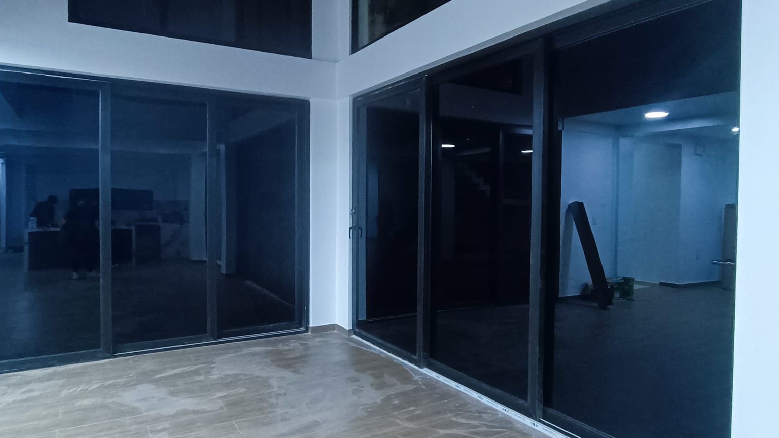 Una habitación con muchas ventanas y puertas de vidrio negro.