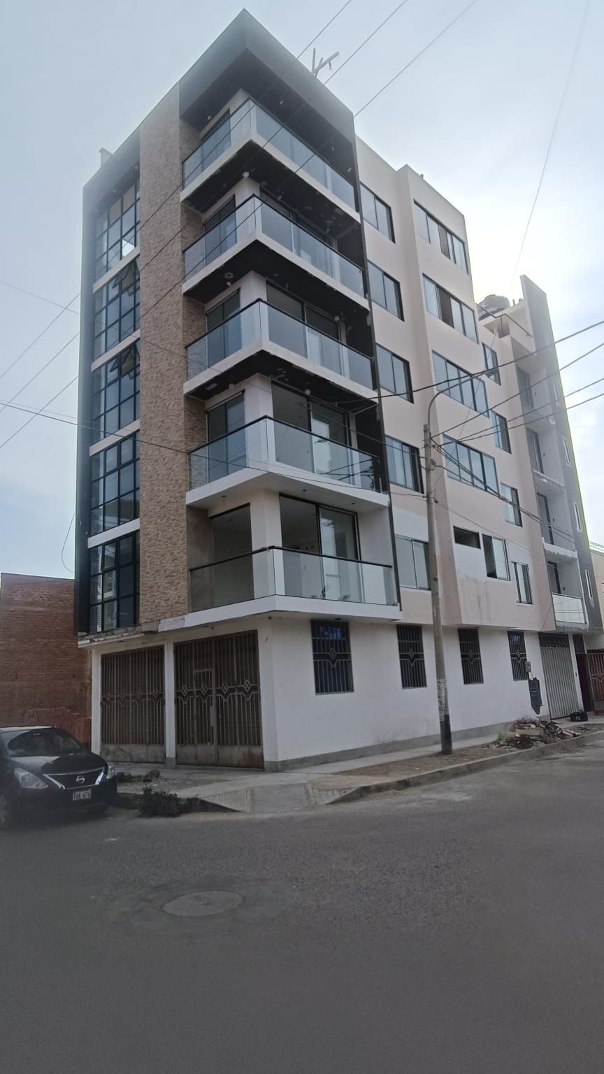 Un edificio alto con muchas ventanas y balcones está situado en la esquina de una calle.