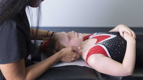 a young girl is laying on a table getting a chiropractic adjustment.