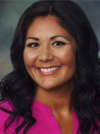 a woman in a pink shirt is smiling for the camera