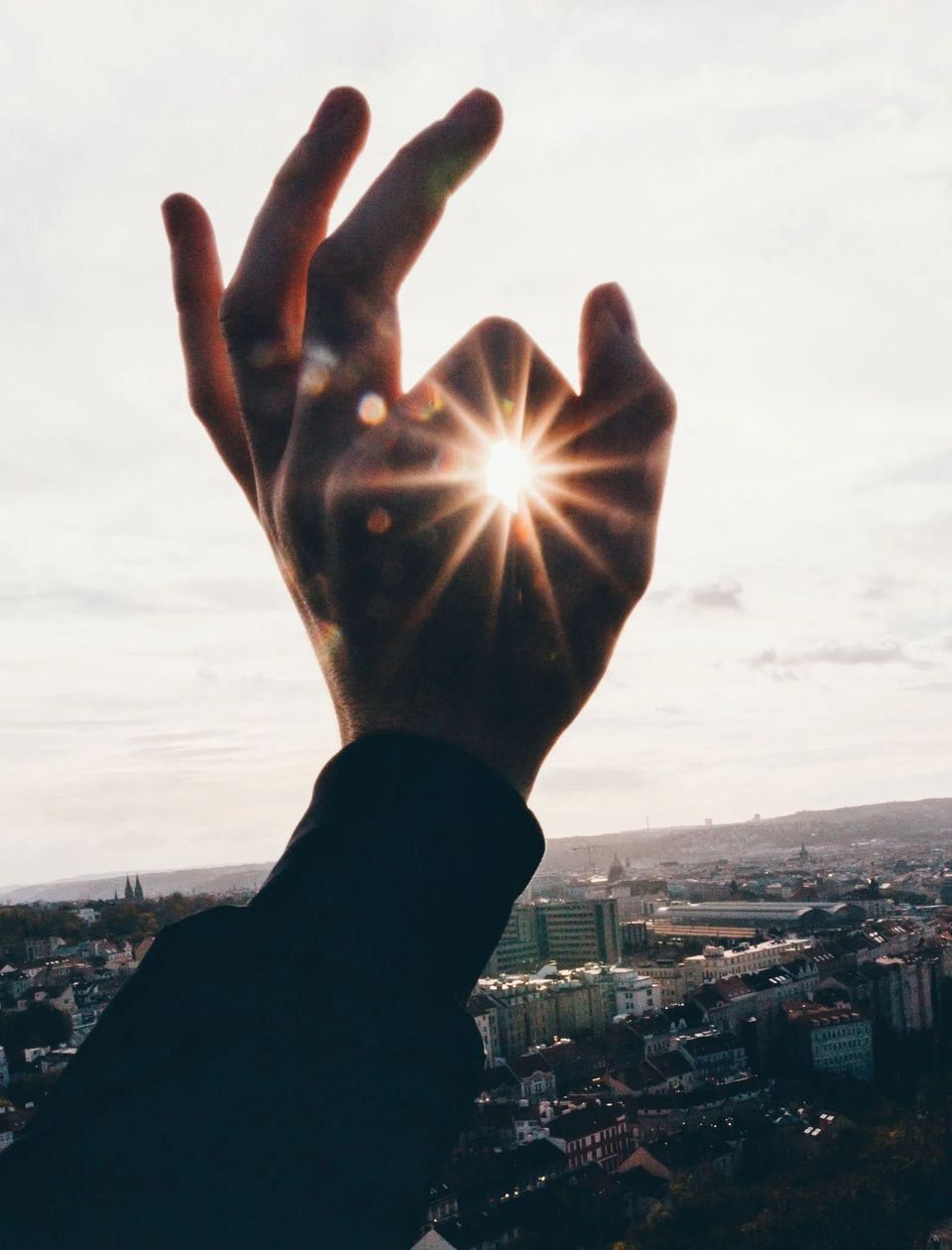 Eine Hand streckt sich nach der Sonne am Himmel aus