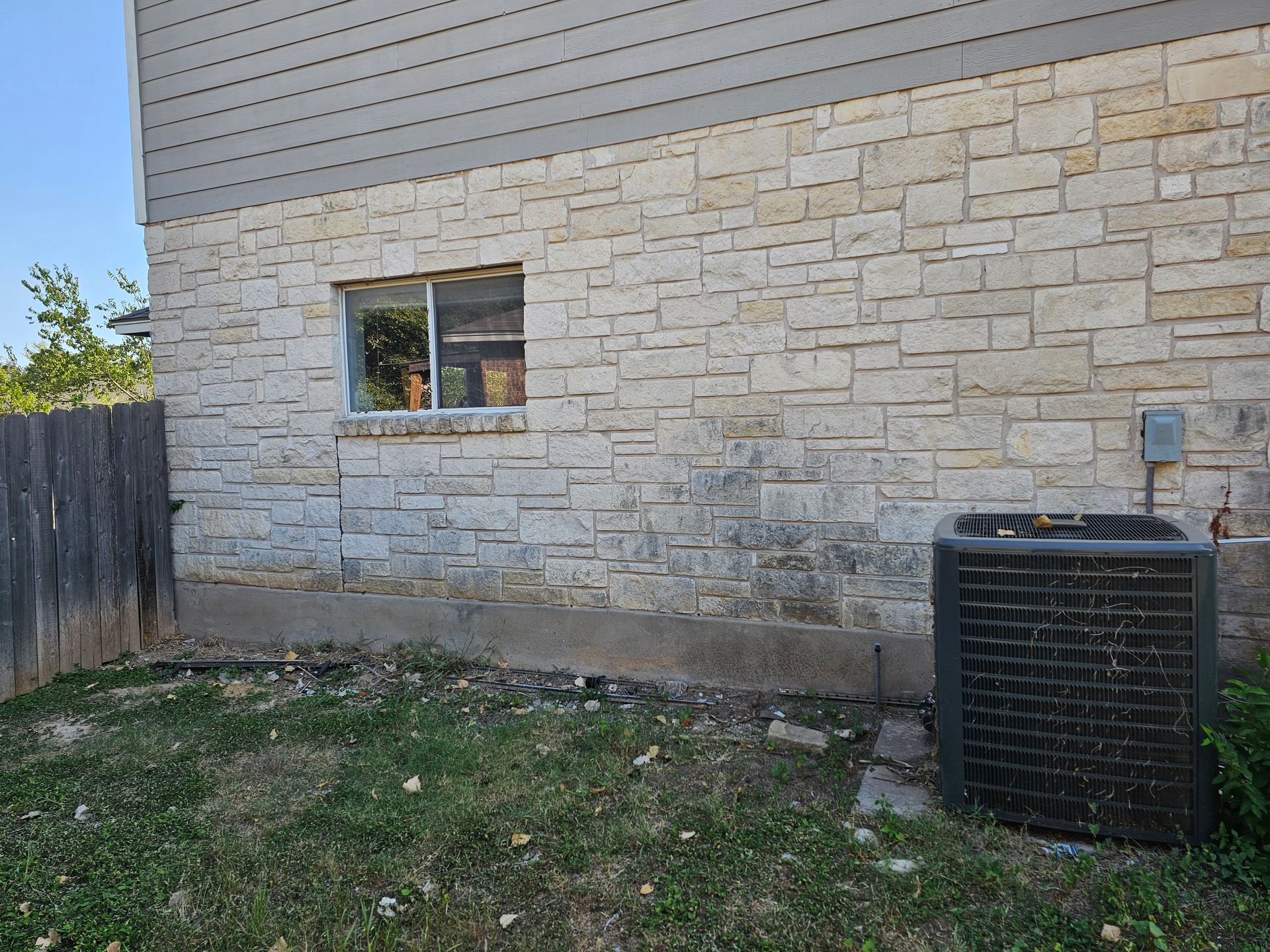 A brick building with a window and an air conditioner in the backyard.