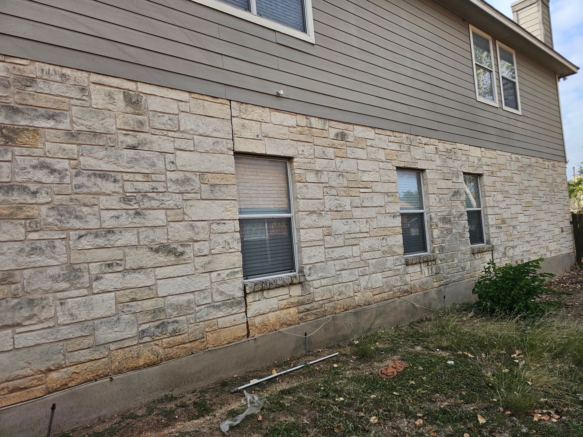 The side of a house with a brick wall and a lot of windows.