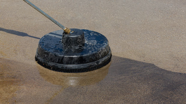 A person is cleaning a concrete surface with a pressure washer.