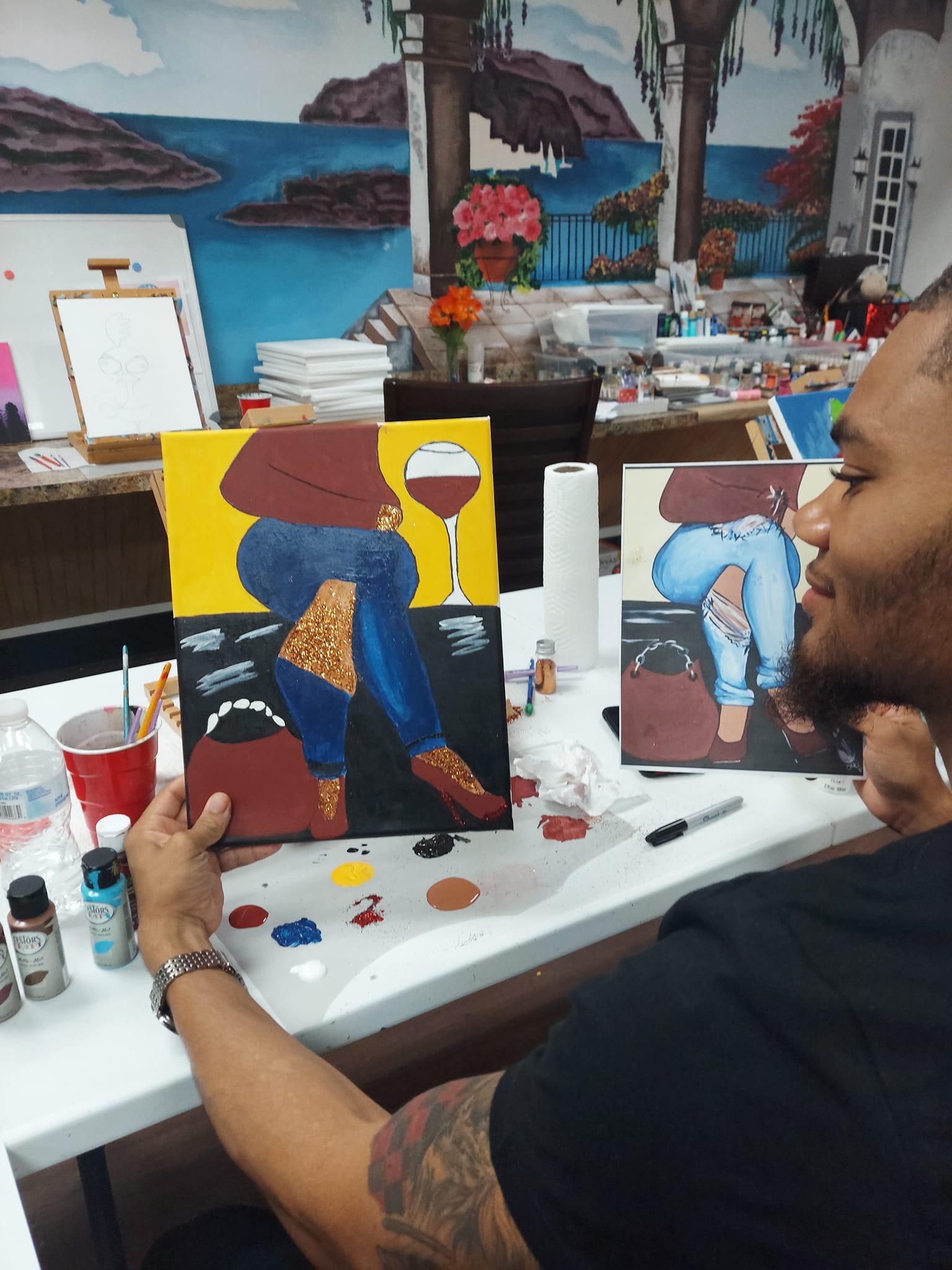 A man is sitting at a table with a painting on it