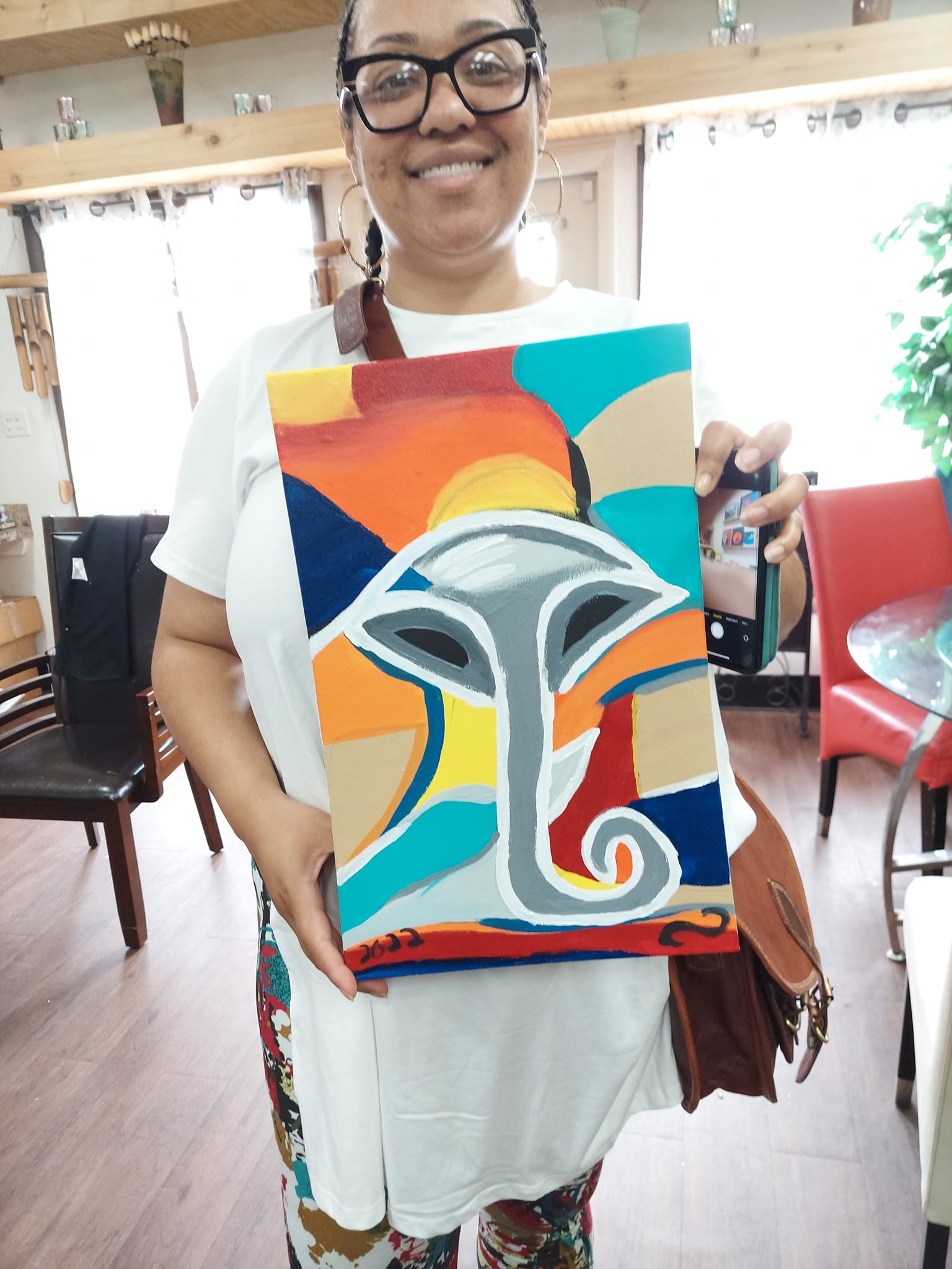 A woman is holding a painting of a mushroom and smiling.