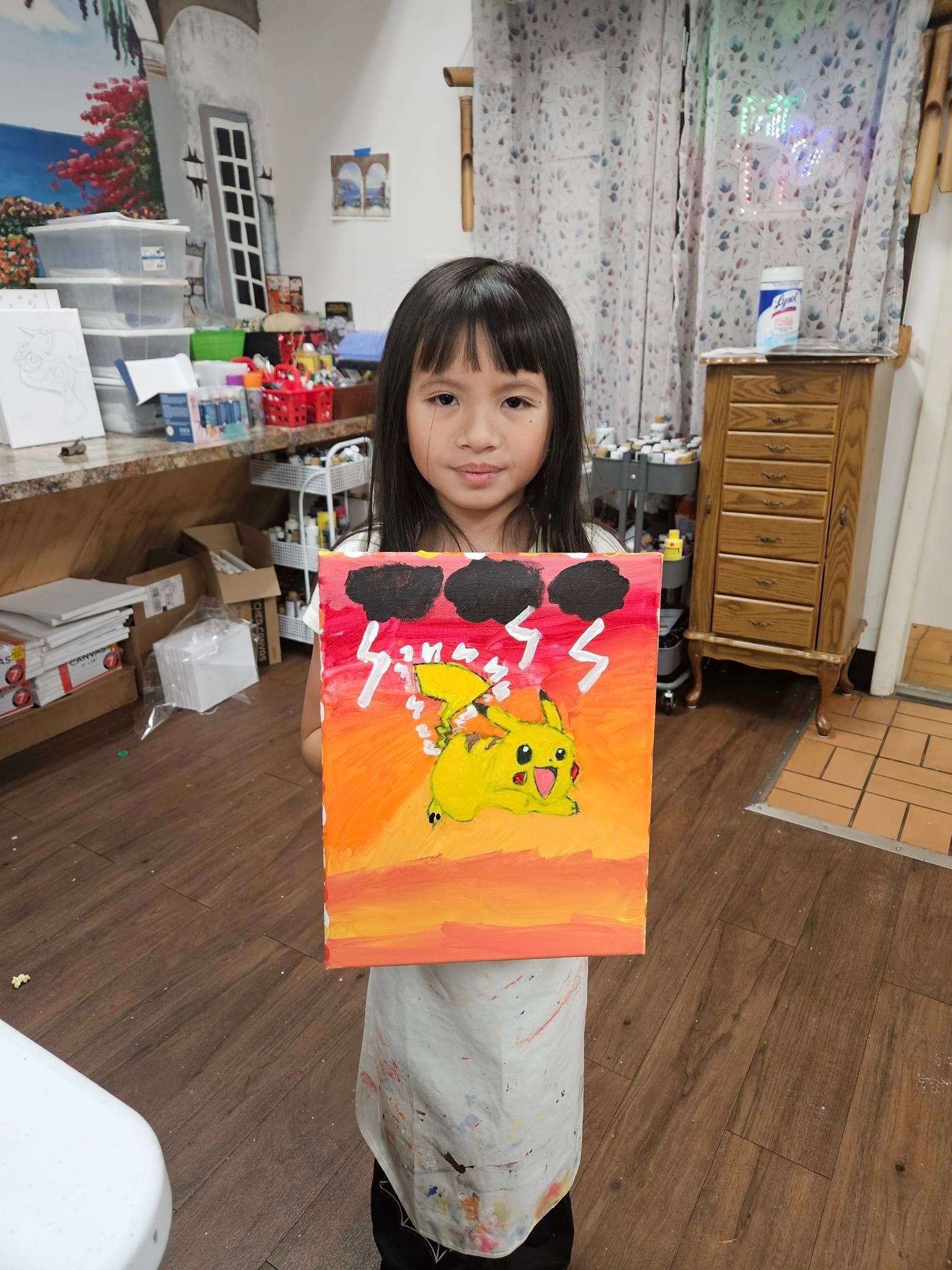 A little girl is holding a painting of a storm in a room.