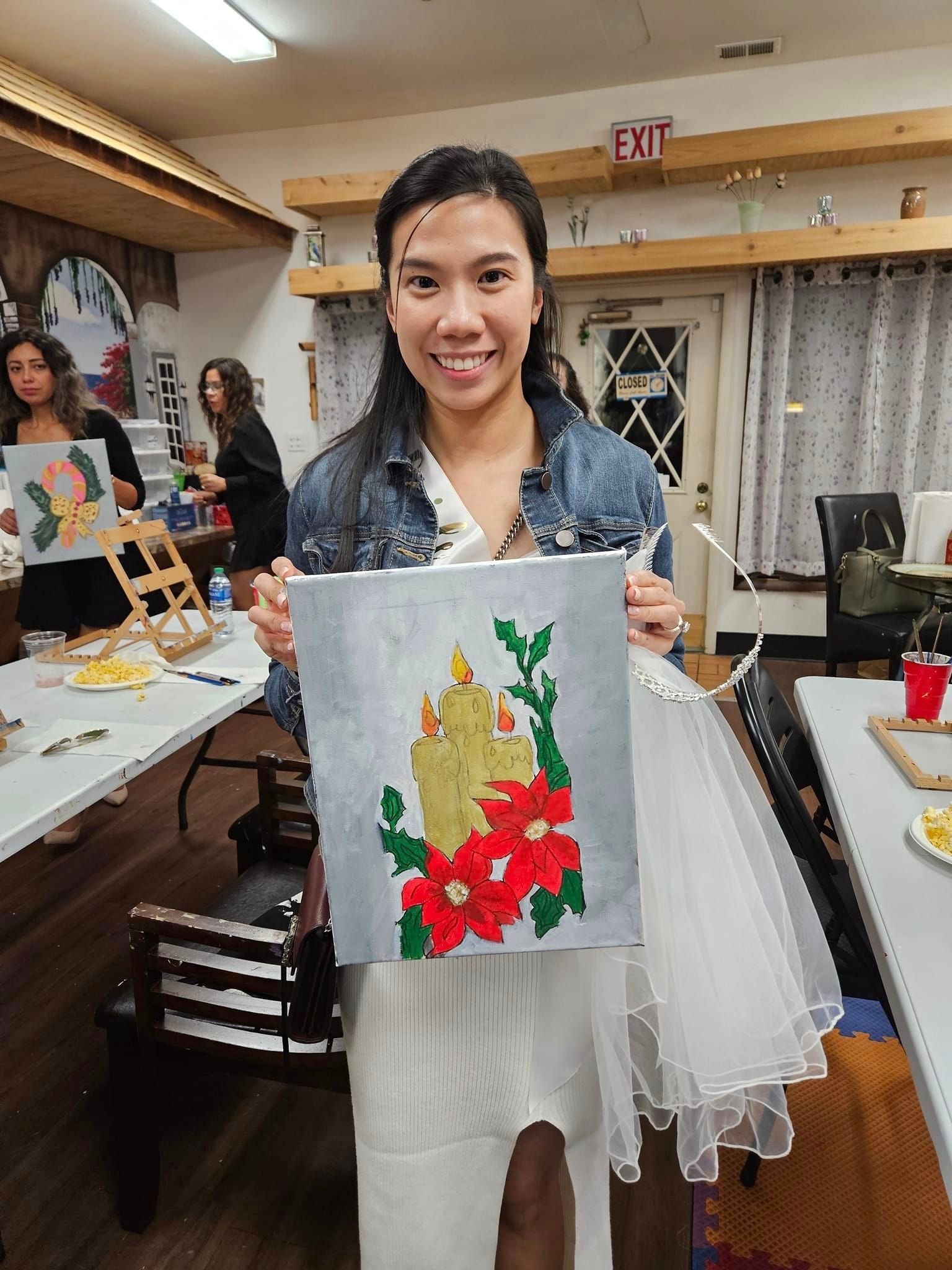 A woman is holding a painting of a cactus in a room.
