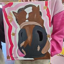 A person is holding a painting of a horse 's head.