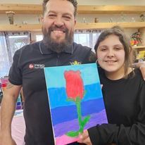 A man and a girl are holding a painting of a rose.