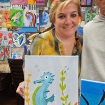 A woman is holding a painting of a seahorse.