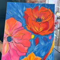 A person is holding a painting of flowers on a blue background.