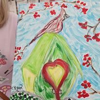 A girl is standing next to a painting of a bird and a heart.