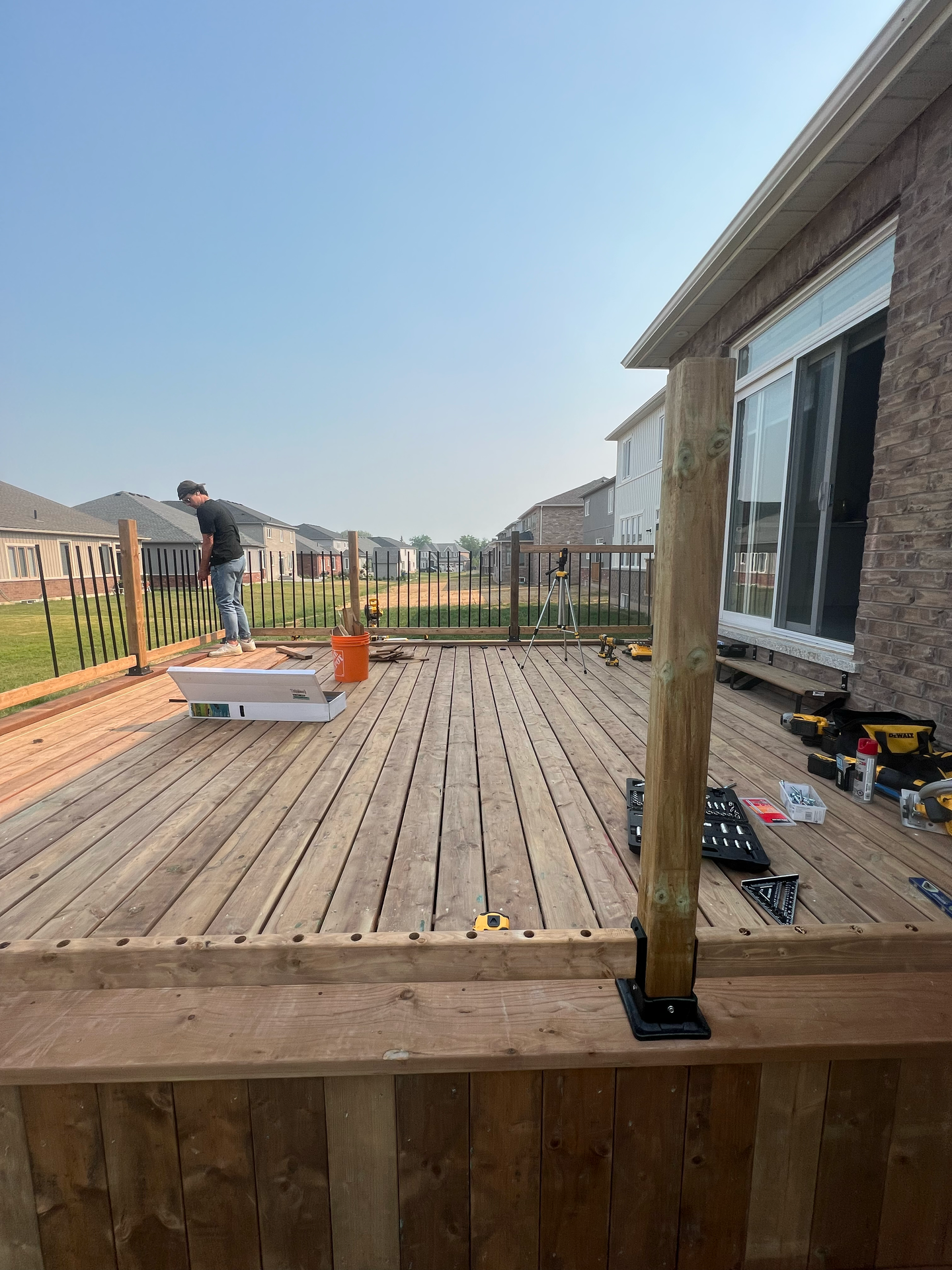 A man is working on a wooden deck in front of a house.