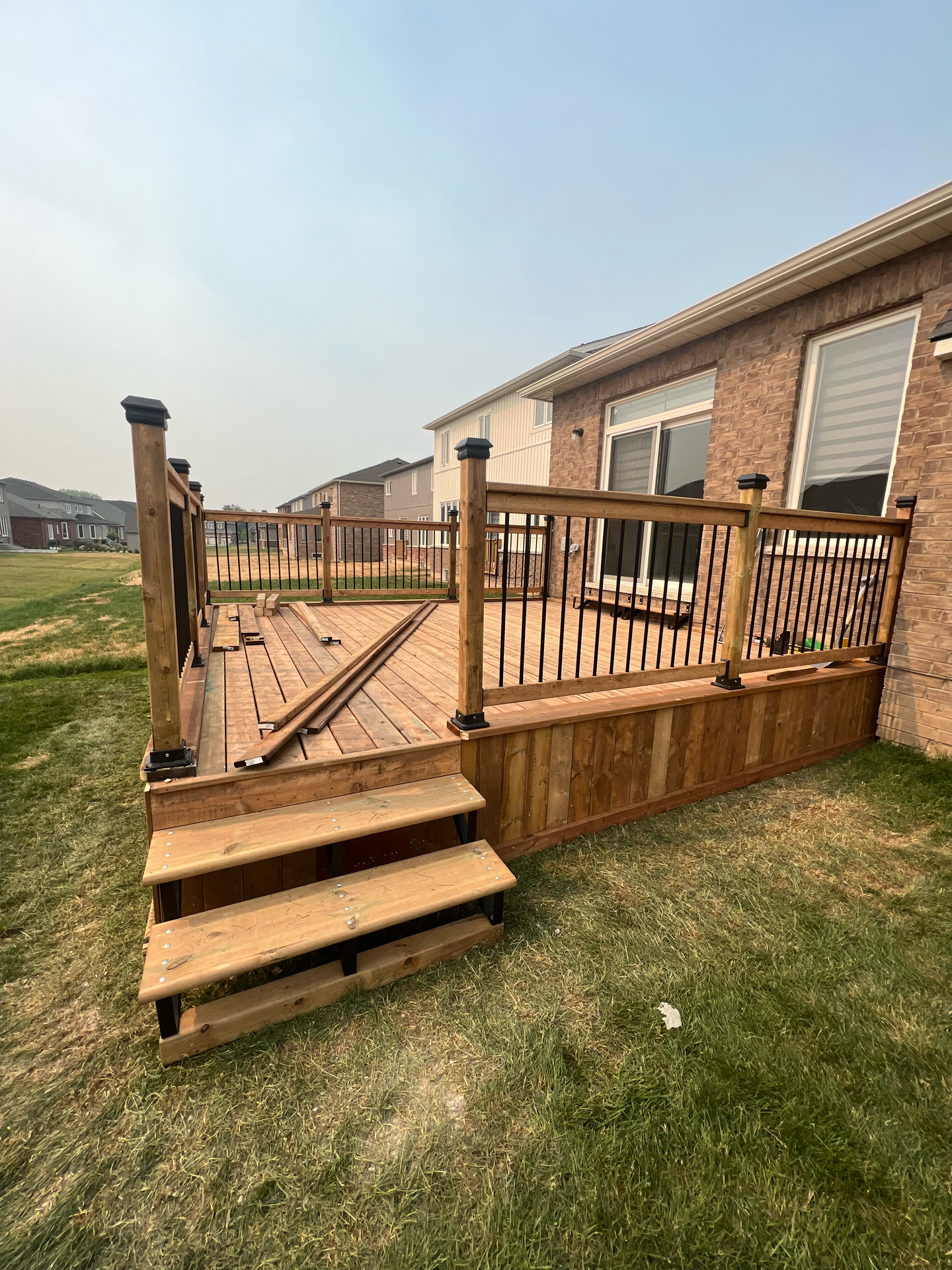 A wooden deck with stairs in front of a brick house.