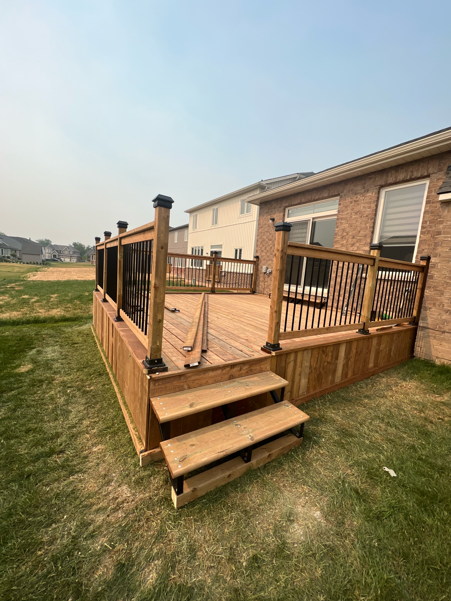 A wooden deck with stairs is in the backyard of a house.