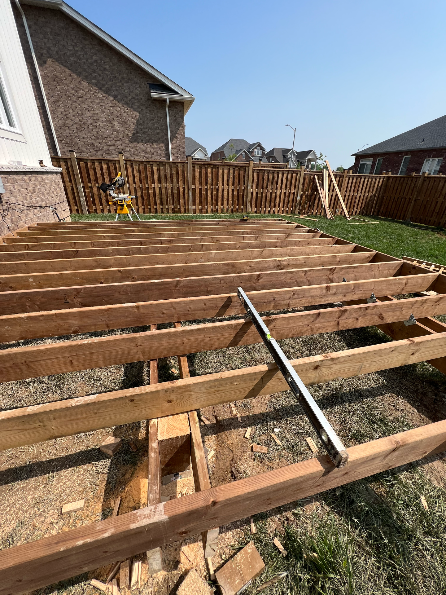 A wooden deck is being built in the backyard of a house.