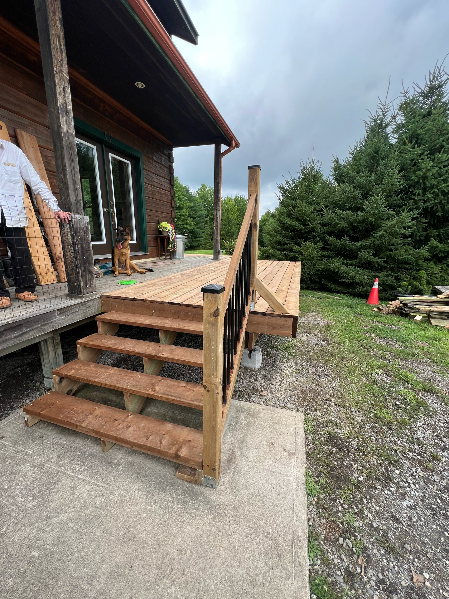 A person is standing on a porch next to a wooden deck.