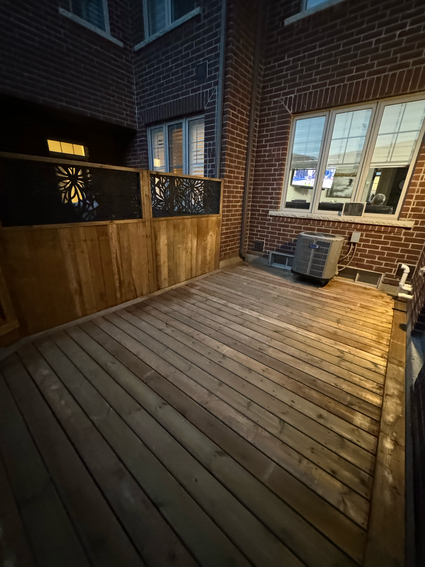 A wooden deck in front of a brick building at night.