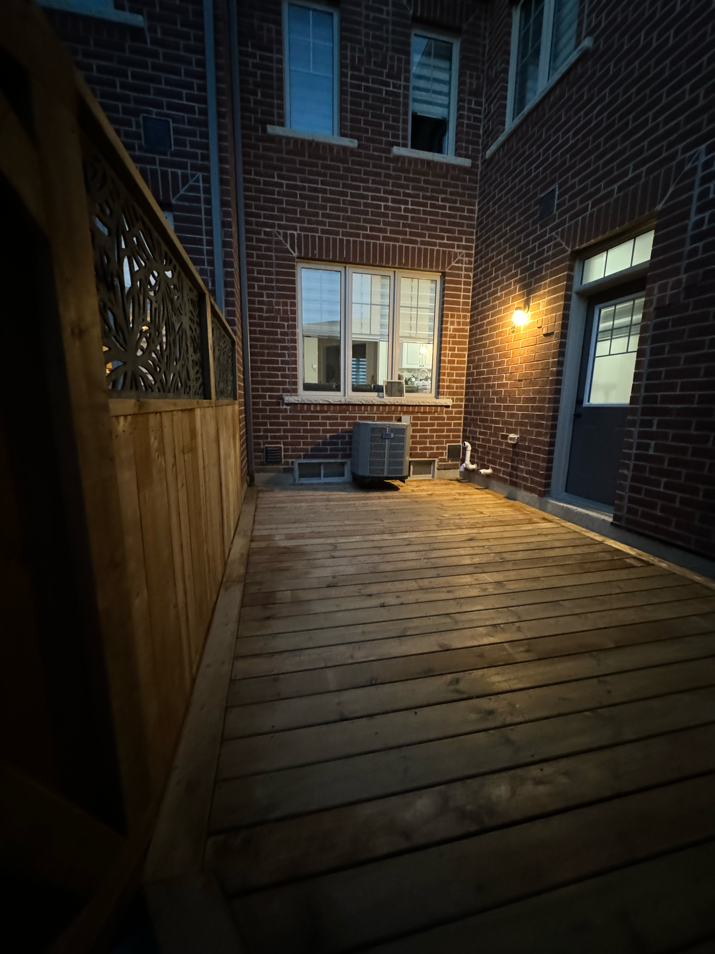 A wooden deck in front of a brick building at night.
