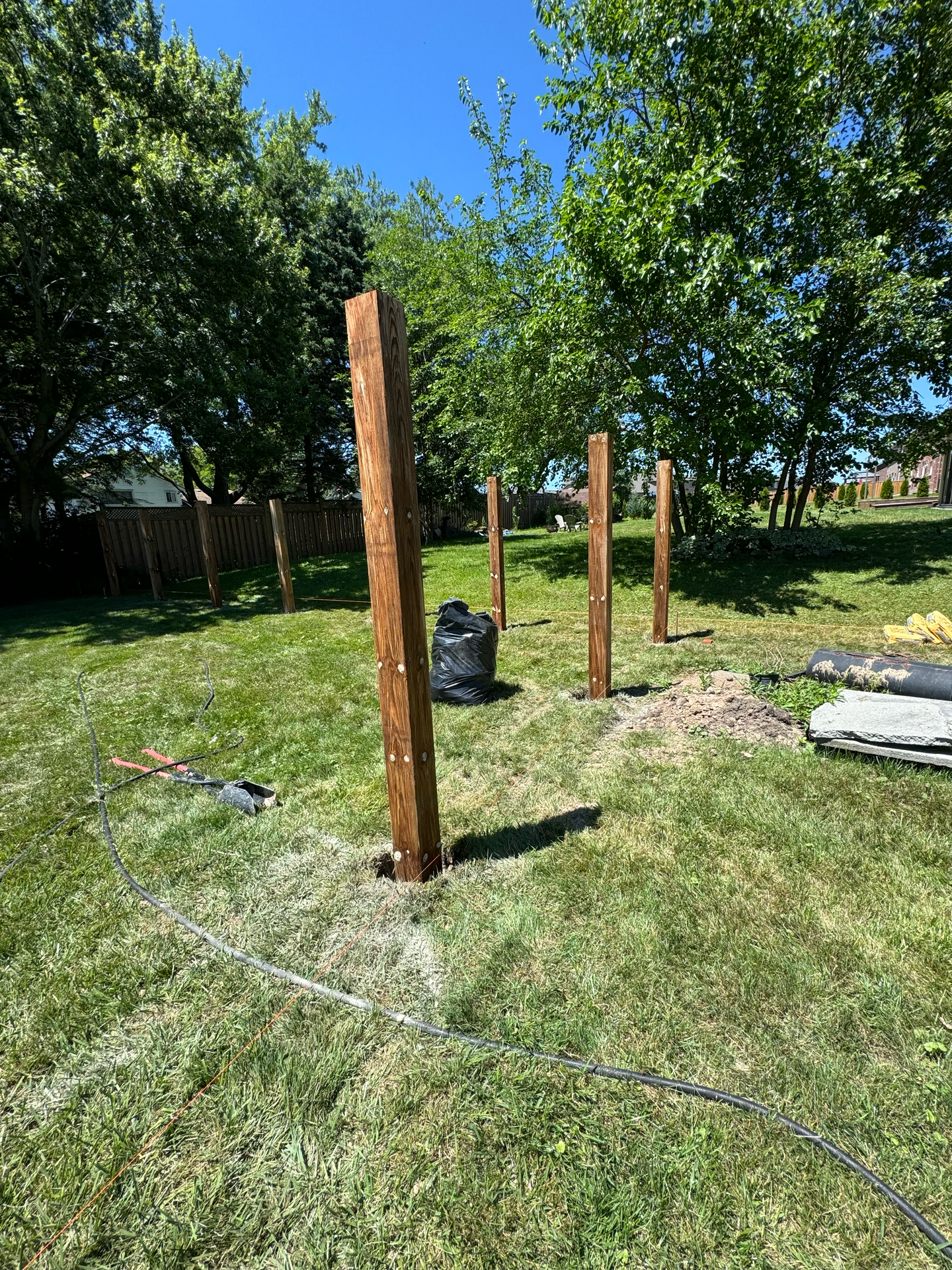 A group of wooden poles are sitting in the middle of a lush green field.