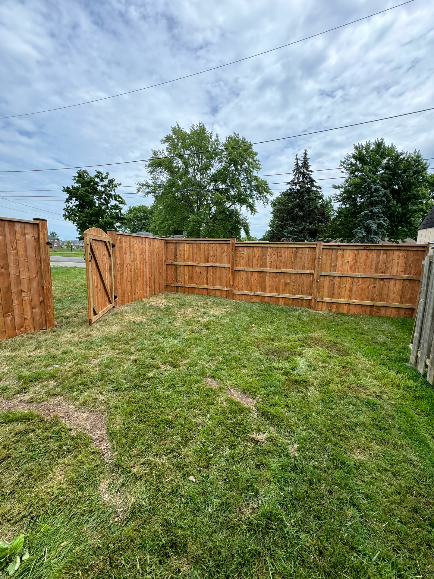 A wooden fence surrounds a lush green yard.