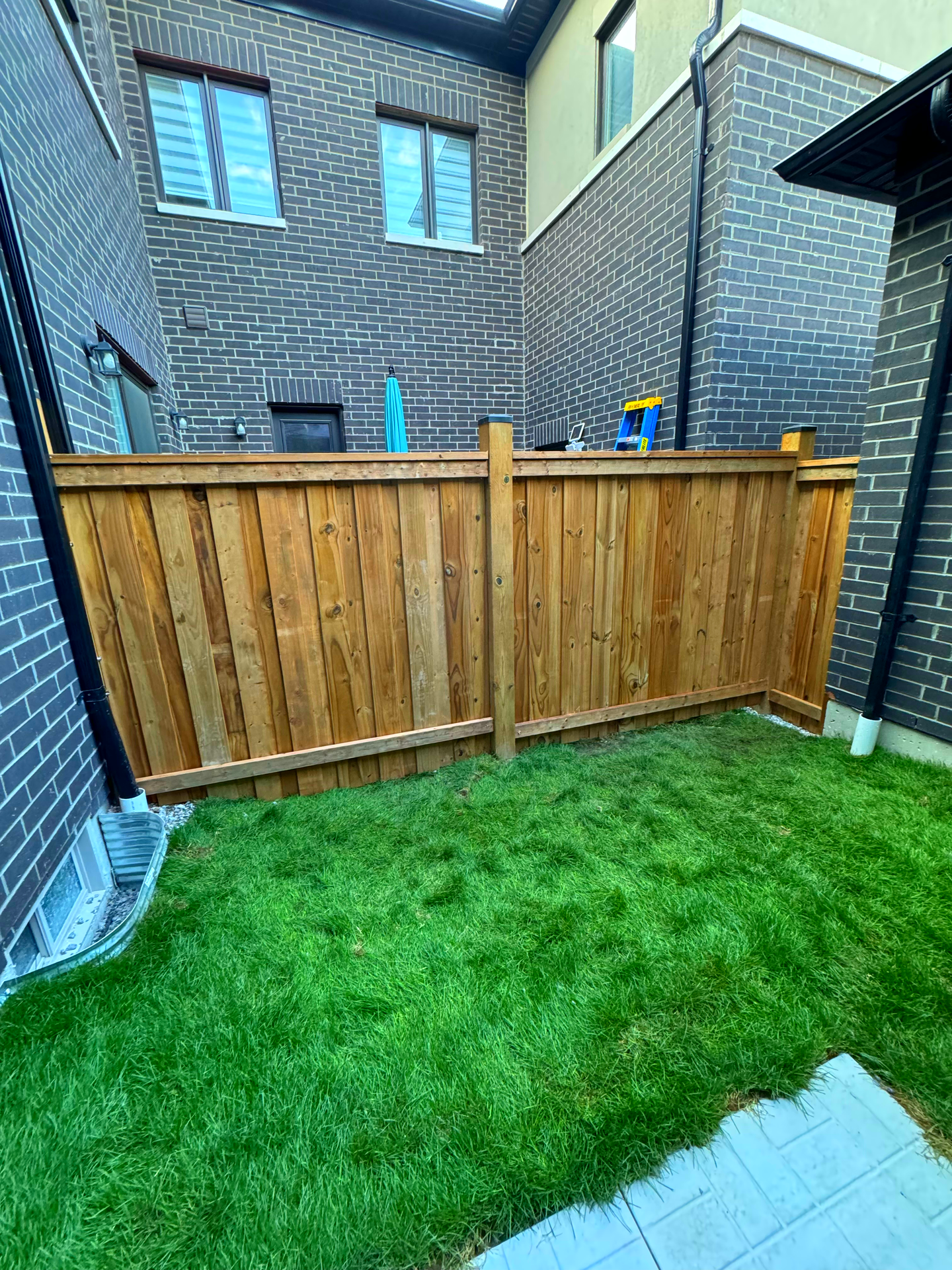 There is a wooden fence in the backyard of a house.