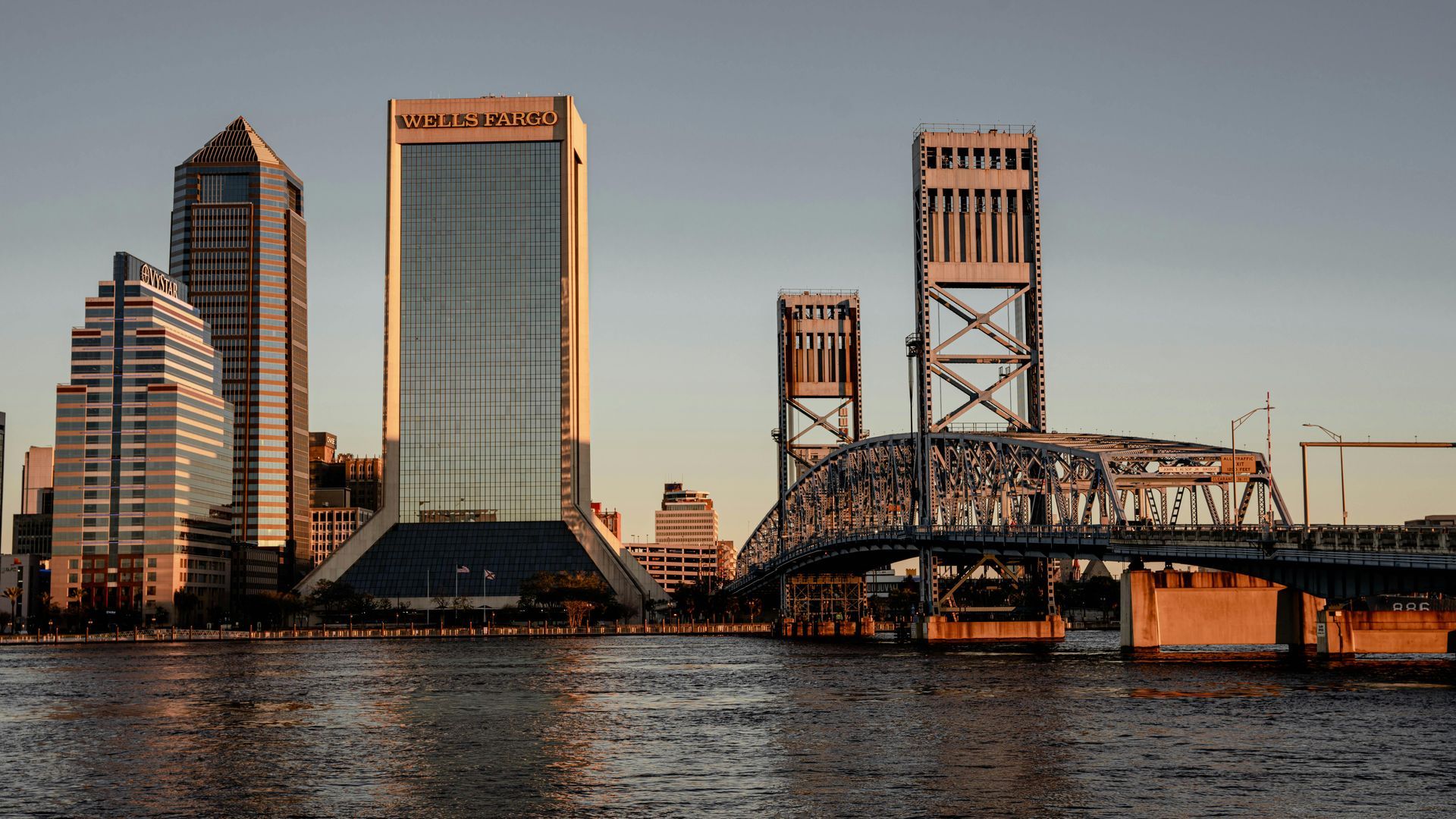 A bridge over a body of water with a city skyline in the background