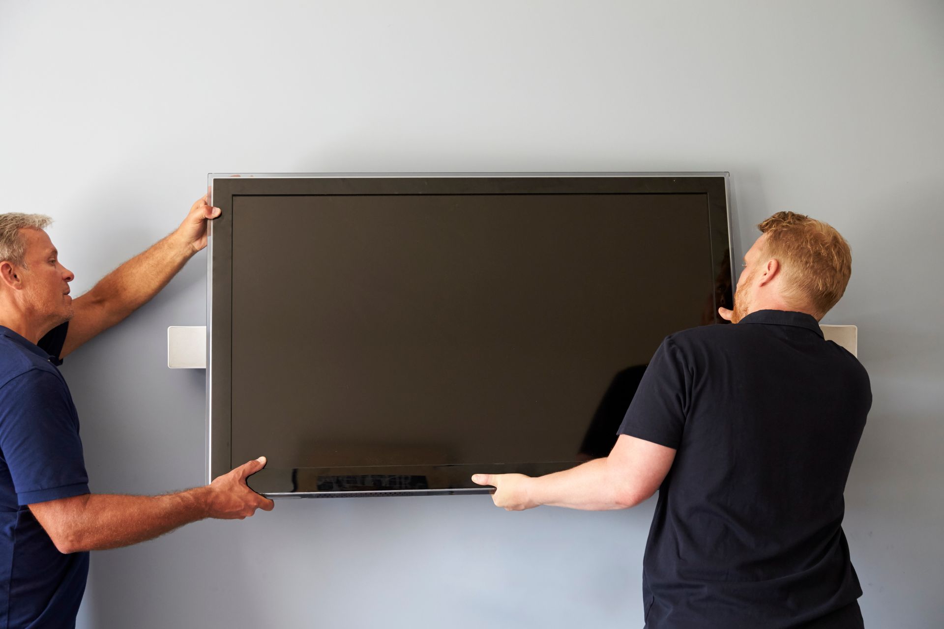 Experienced Pro Touch Movers technician carefully attaching a television wall mount