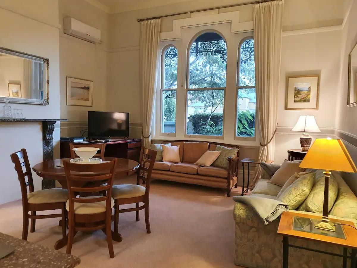 A Living Room With A Couch, A Table And Chairs — Accommodation in Forbes, NSW