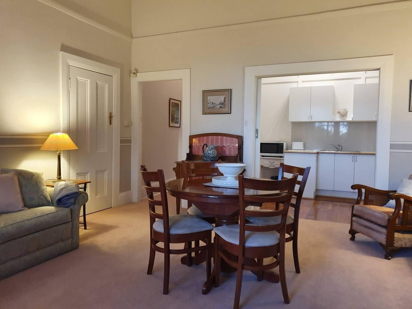 A Living Room With A Wooden Dining Table And Chairs — Accommodation in Forbes, NSW