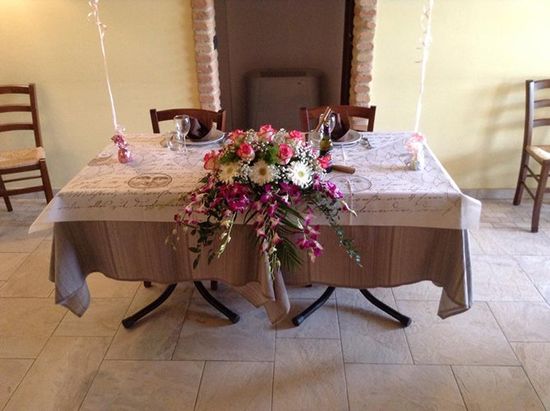 Un tavolo con una tovaglia,un bouquet di fiori, due piatti e due bicchieri 