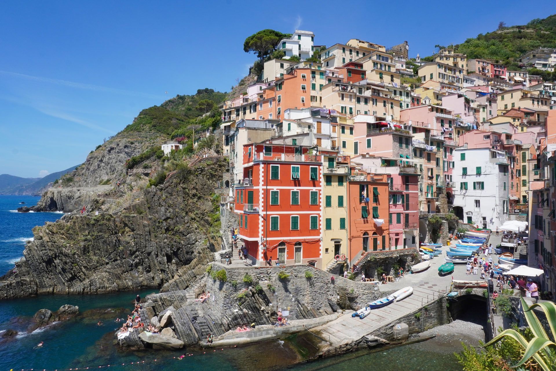 Colorful buildings stacked on a seaside cliff in Riomaggiore, Italy, with blue water and sky.