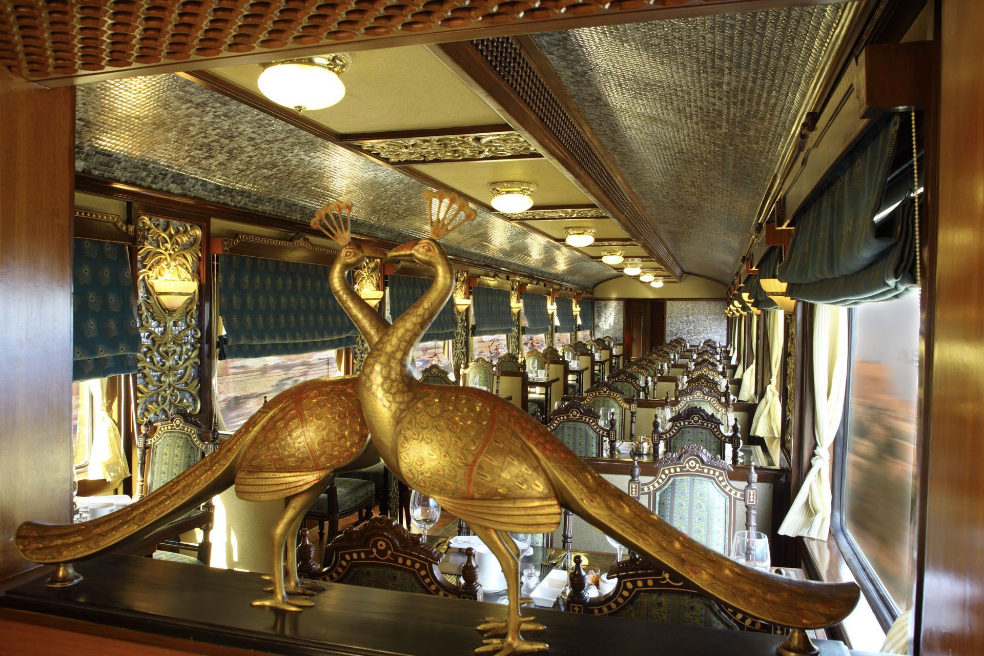 Golden swan statues in a mirrored hall with ornate, reflective ceiling panels and lights